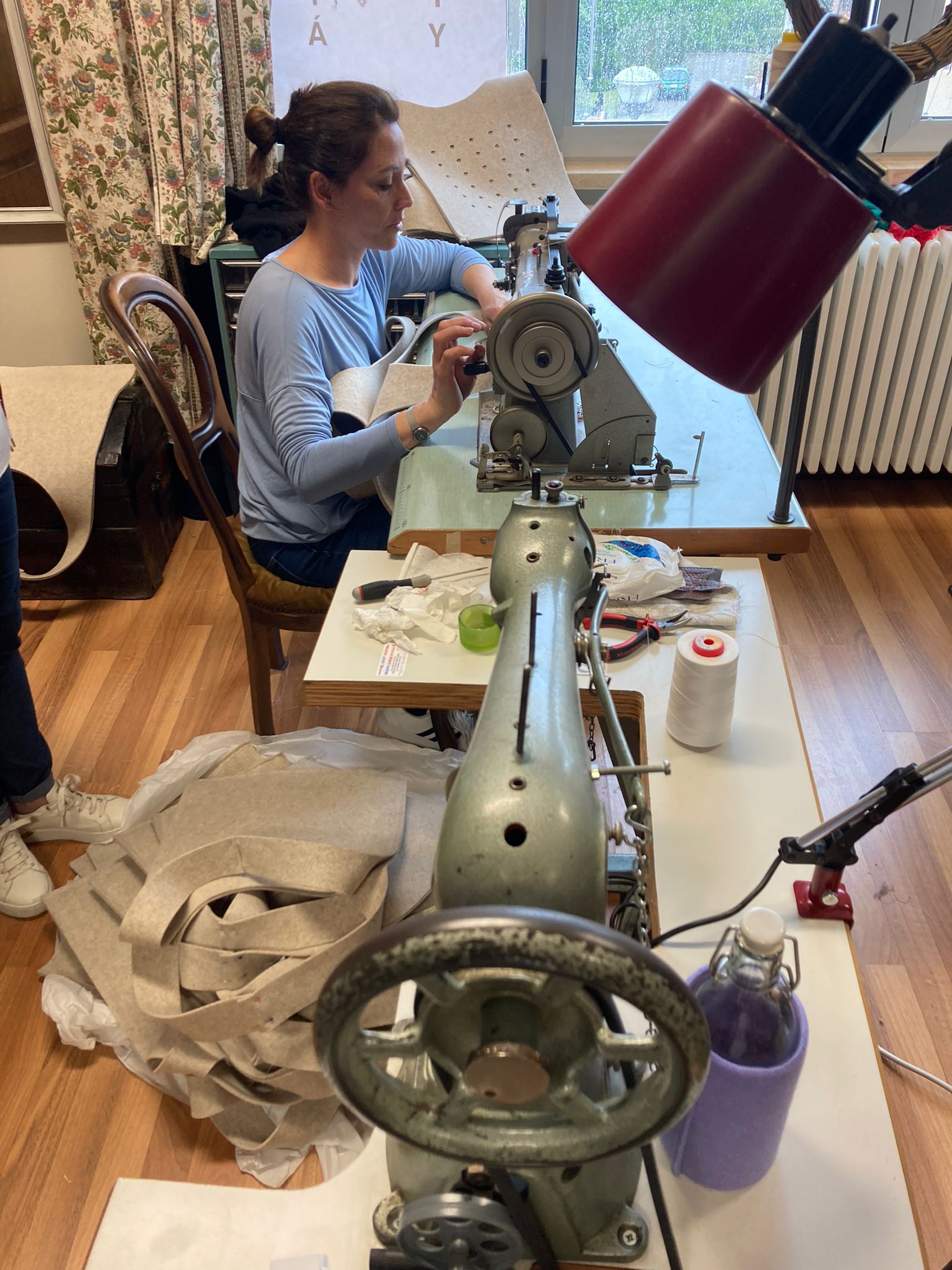 Una donna concentrata mentre cucisce una borsa in feltro sostenibile. L'immagine rappresenta il lavoro artigianale e l'imprenditoria femminile nel settore del packaging sostenibile. Simboleggia l'azienda Basiliotti che promuove la parità di genere e l'innovazione ambientale nell'industria.