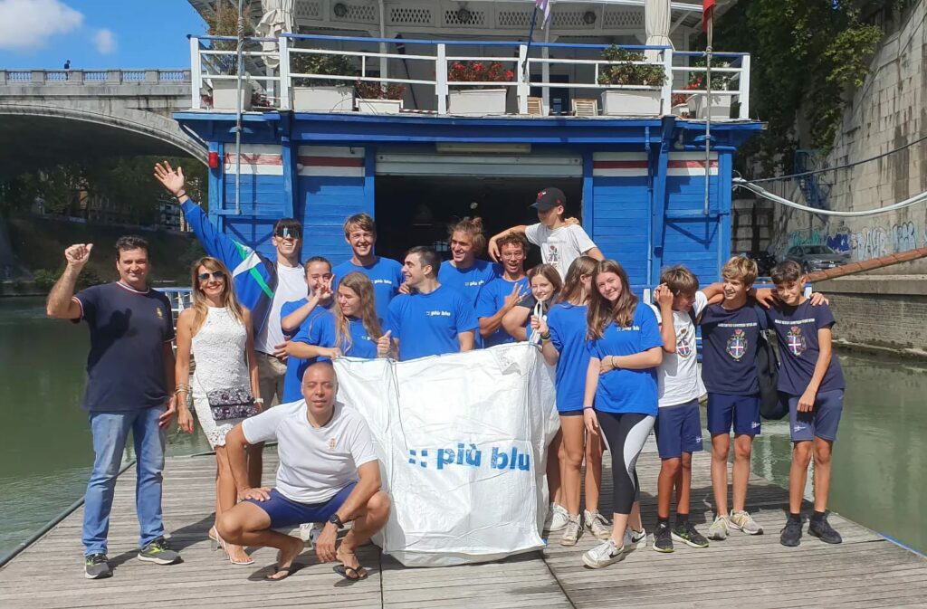 Gruppo di volontari partecipanti all'iniziativa di pulizia del Tevere organizzata da Basiliotti, azienda specializzata in packaging sostenibile. Gli attivisti stanno lavorando insieme per rimuovere i rifiuti plastici dalle sponde del fiume e contribuire alla salvaguardia dell'ambiente.